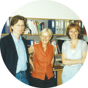 Ein altes Foto von 1997. Damals wurden die ersten Kurse für Menschen mit Behinderung geplant. Es stehen Gerhard Bisovsky, Ilona Weigl und Beatrix Eder-Gregor in einem Büro stehen. Sie lächeln in die Kamera.