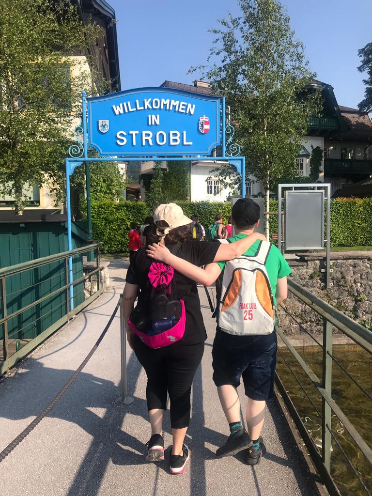 Am Wolfgangsee kann man auch mit dem Schiff fahren. Bei der Anlegestelle in Strobl am Wolfgangesse gehen zwei Teilnhemerinnen Arm in Arm den Steg entlang. Vor ihnen ist ein Tor mit einem großen Schild auf dem steht: "Willkommen in Strobl."